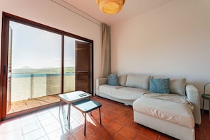 Una sala de estar con sofá, una mesa y vistas a través de un ventanal.