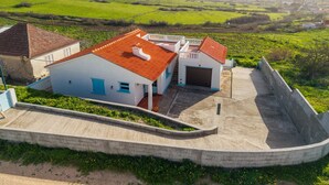 A white building with a red roof, a garage, and a concrete wall. - Sailor House - By Wehost (Porto Santo)