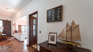 A wooden desk with a model ship, a framed picture, and a wall-mounted sign with text. - Sailor House - By Wehost (Porto Santo)