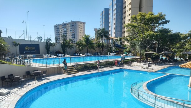 Una piscina con bordo piastrellato, poltrone a sdraio e un cartello con la scritta 'Golden Dolphin'.
