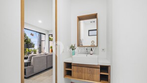 Een moderne badkamer met een wit wastafelmeubel, een houten kast en een grote spiegel.