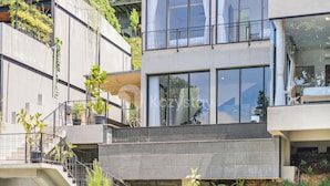 Een modern gebouw met meerdere balkons, grote ramen en plantenbakken.