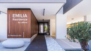 Un edificio moderno con fachada de madera y un letrero que dice 'EMILIA Residence by Lebrus 52 Medousis Str.'