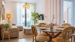 Una sala moderna con una mesa de comedor de vidrio, sillas de mimbre, un sofá, una mesa de centro y una planta en maceta.
