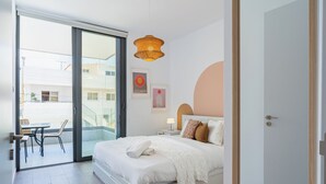 Un dormitorio moderno con una cama grande, un balcón y vistas a edificios.