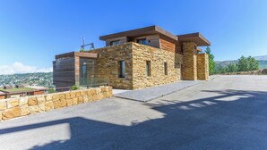 A modern building with stone and wood exterior, large windows, and a flat roof. - RedRock Faqra - Mountain Getaway Residences W Pool & Balconies (Bqaatouta)