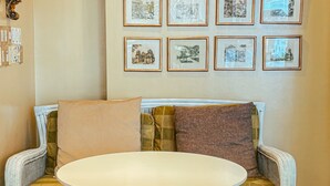 A room with a sofa and a round table. There are framed pictures on the wall. - La Mansion Tagaytay (Tagaytay)