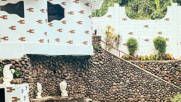 A pool area with a stone wall, a small waterfall, and decorative statues. - La Mansion Tagaytay (Tagaytay)