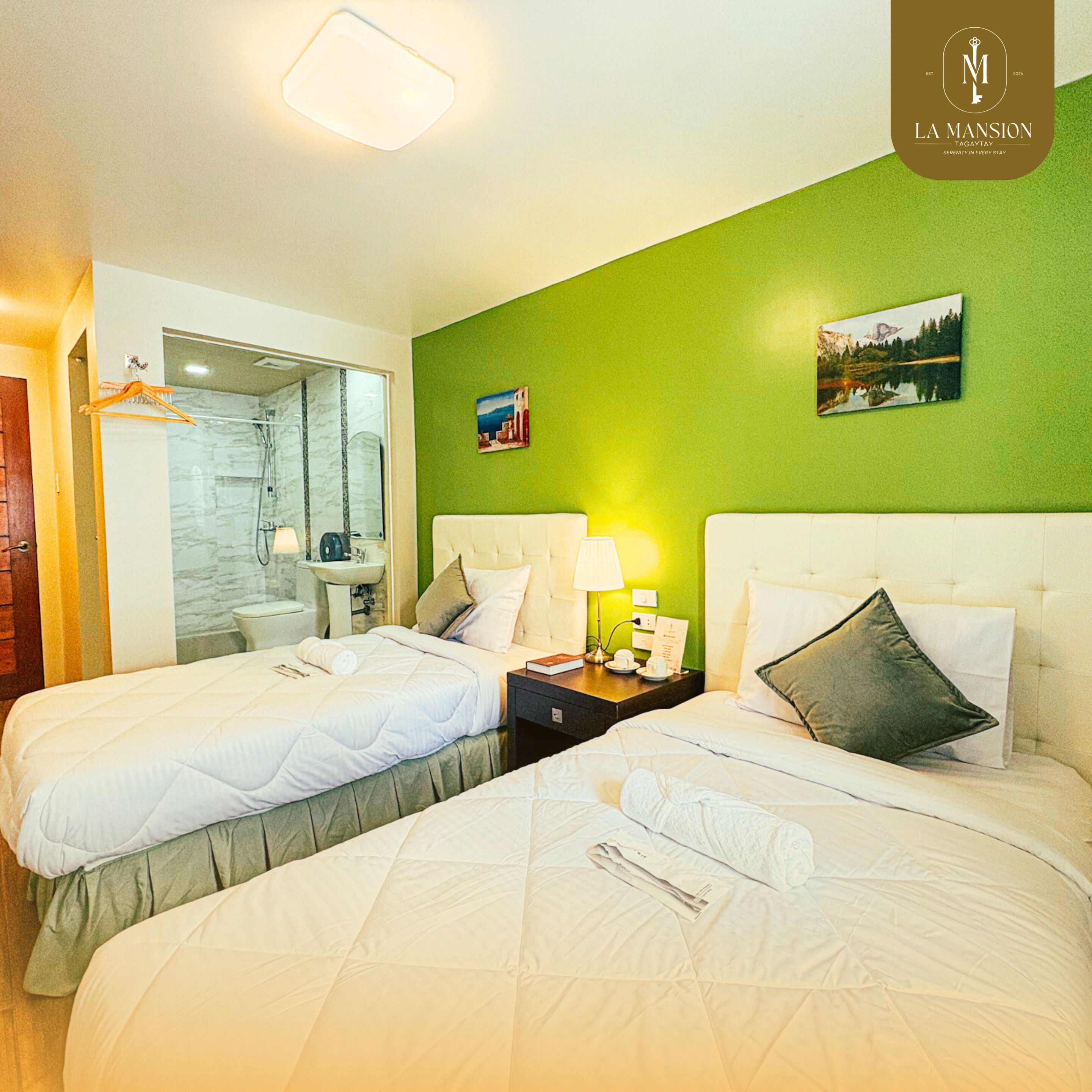 Une chambre d’hôtel avec deux lits, une salle de bain et un mur vert.