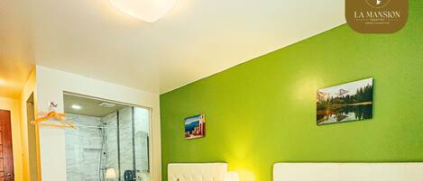 Habitación de hotel con dos camas, baño y pared verde.