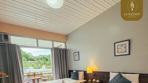 A hotel room with two beds, a balcony, and a view of greenery. - La Mansion Tagaytay (Tagaytay)