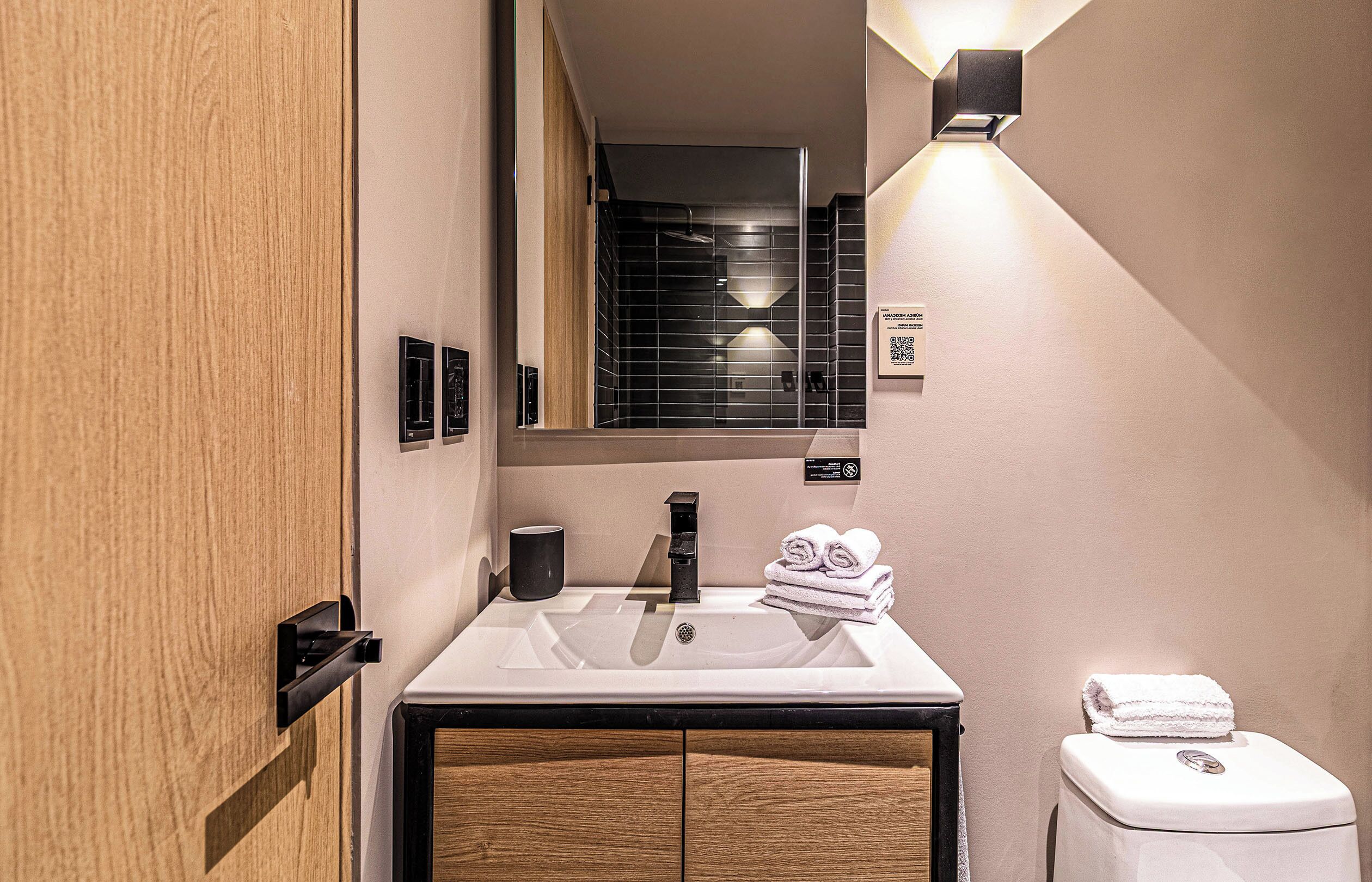 A modern bathroom with a sink, mirror, towel rack, and toilet.