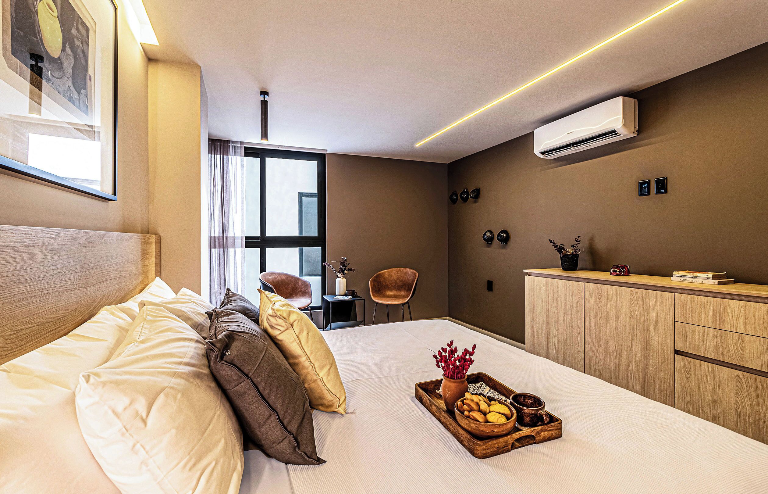 Una habitación de hotel moderna con cama, mesita de noche y vistas a la ciudad.
