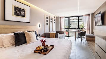 Habitación de hotel moderna con una cama grande, un área de comedor y vistas a la ciudad.