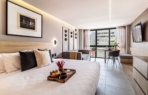 A modern hotel room with a large bed, a dining area, and a view of the city. - Kukun Tonalá 121 Roma  (Mexico City)