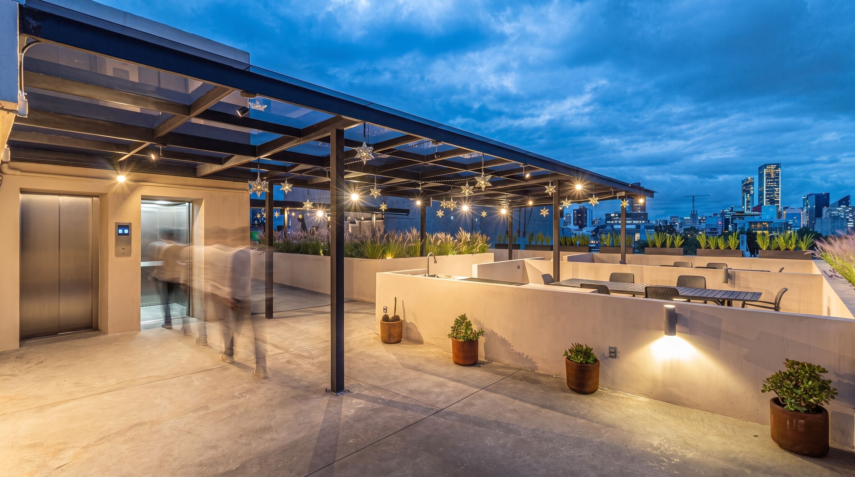 An outdoor rooftop terrace with a city skyline view, seating areas, and a covered section with star-shaped lights.