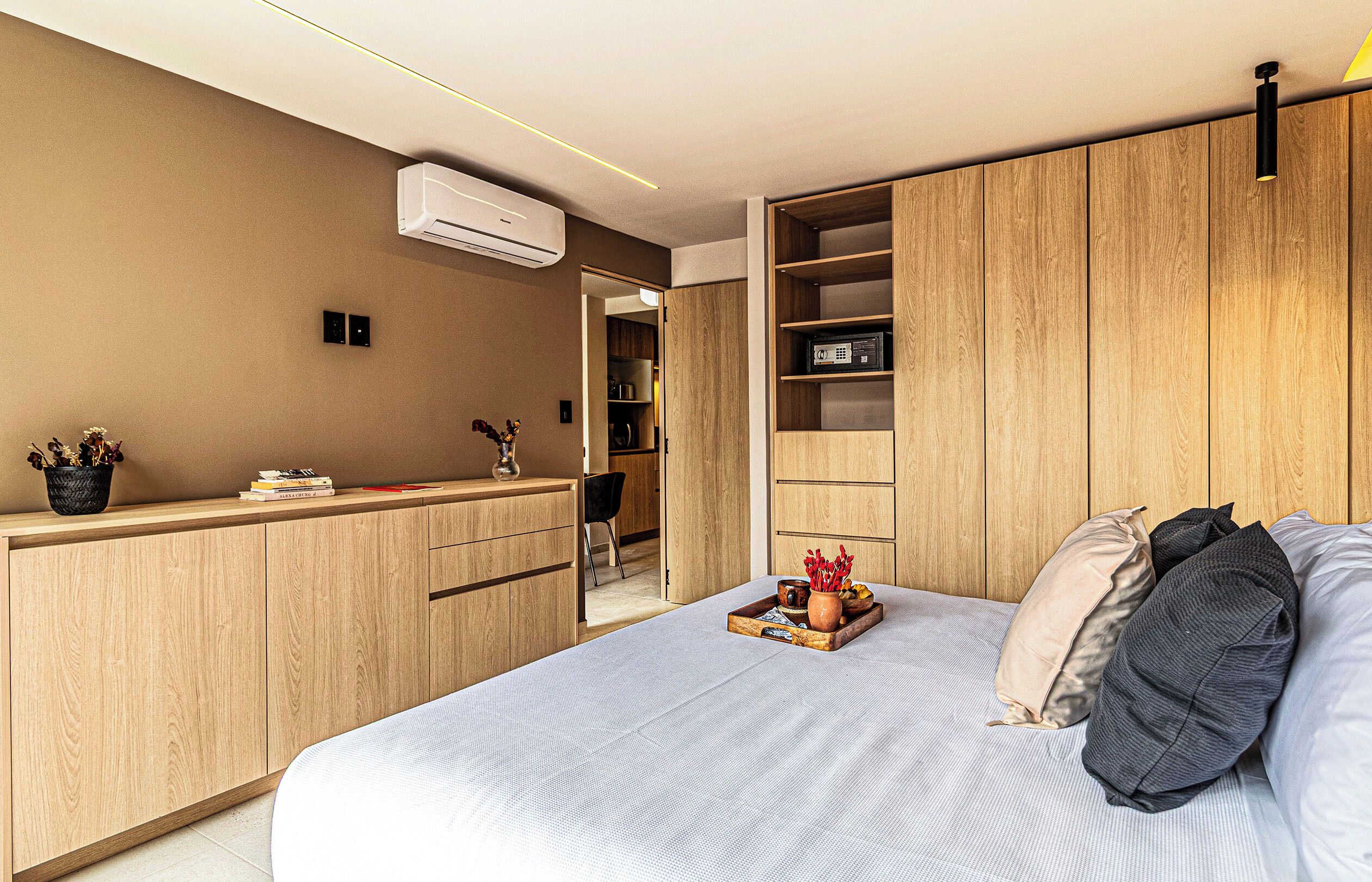 Ein modernes Schlafzimmer mit Bett, Nachttischen, einem Kleiderschrank und einer eingebauten Regaleinheit.