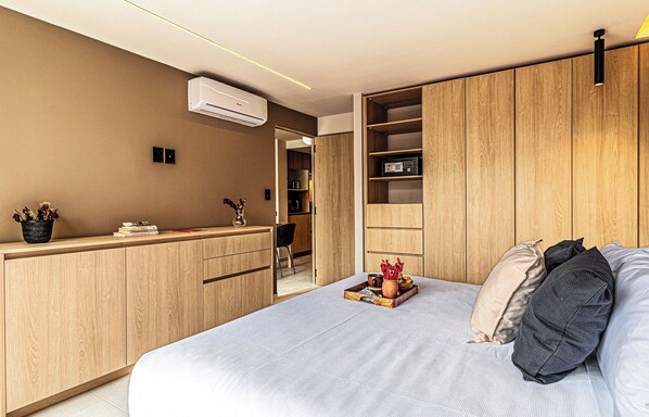 Un dormitorio moderno con cama, mesitas de noche, armario y estantería empotrada.