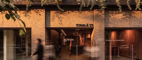 Un edificio moderno con un letrero que indica 'TONALÁ 121' y 'KUKUN ROMA', señal de ser un hotel u otro establecimiento similar.