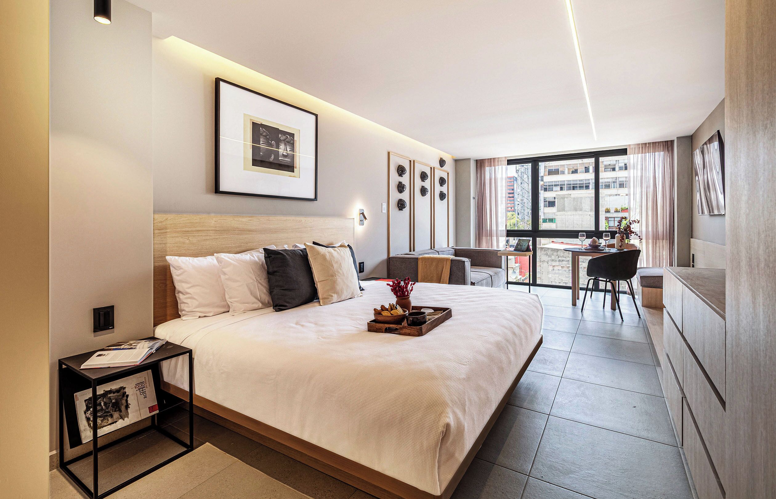 Une chambre d’hôtel moderne, dotée d’un grand lit, d’un bureau et offrant une vue sur la ville par la fenêtre.