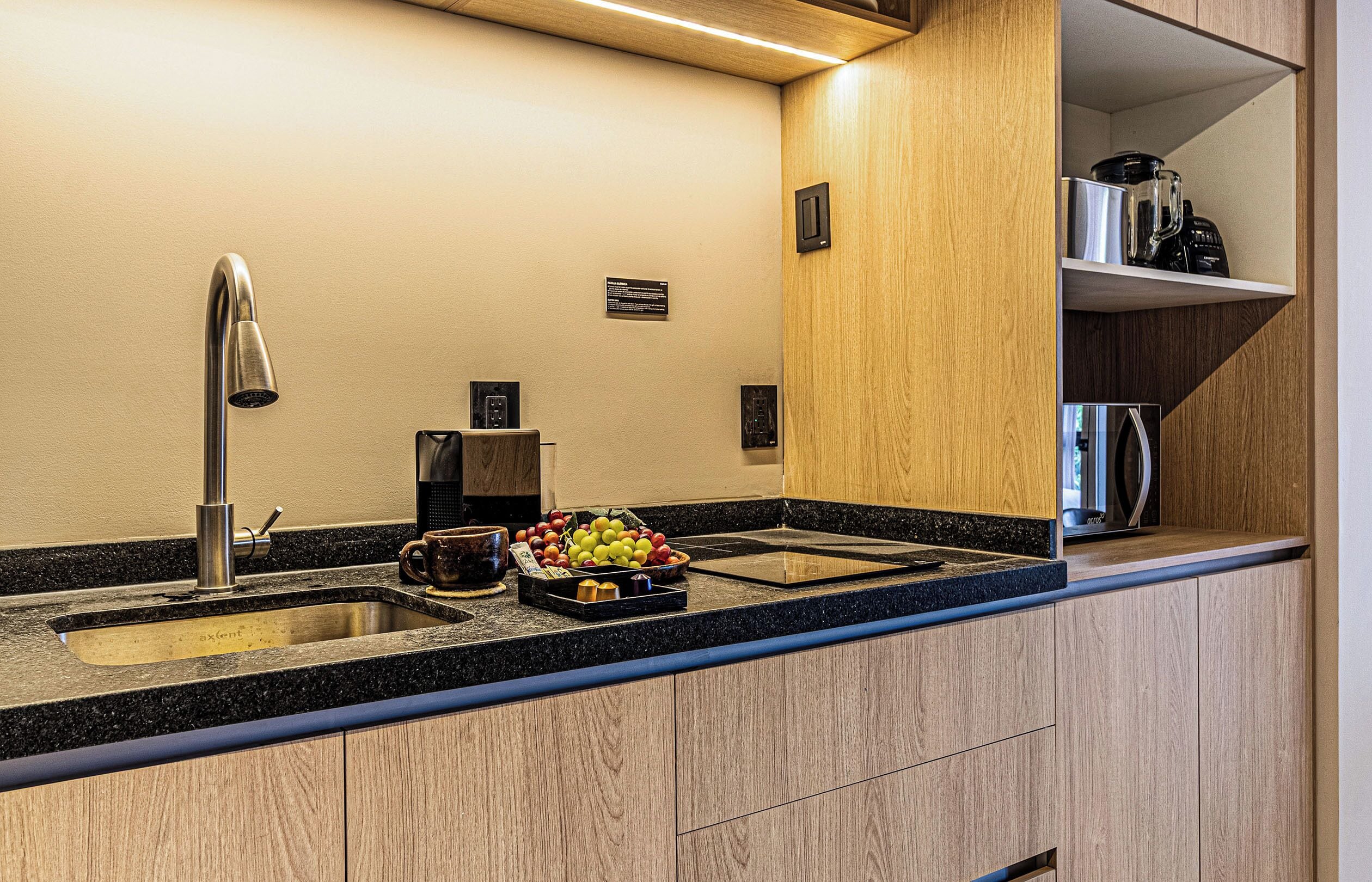 A modern kitchen with a double sink, a coffee machine, and a fruit bowl on the counter.
