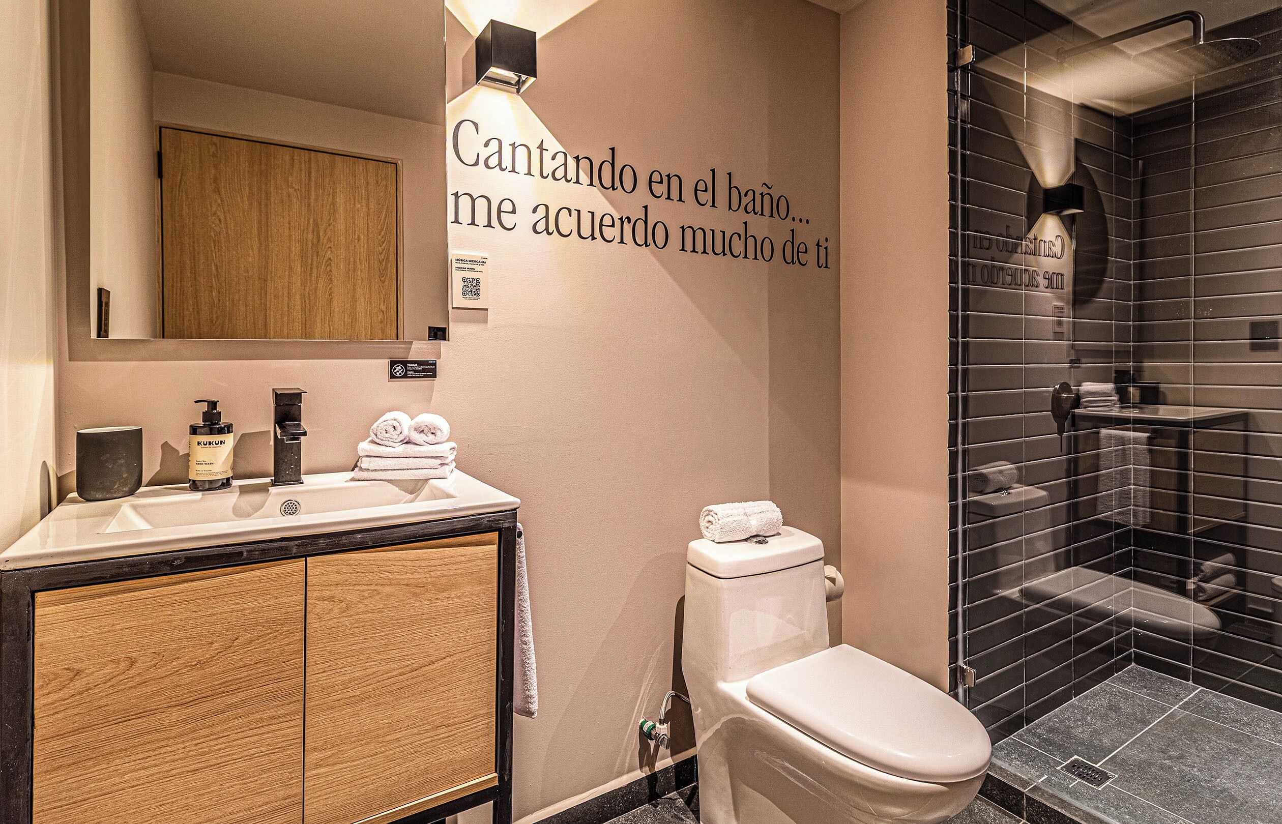 A modern bathroom with a sink, mirror, and a wall-mounted toilet.
