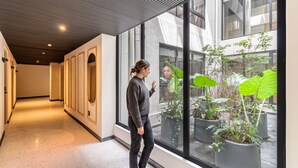 A corridor with a reflective glass wall and potted plants. - Kukun Tonalá 121 Roma  (Mexico City)