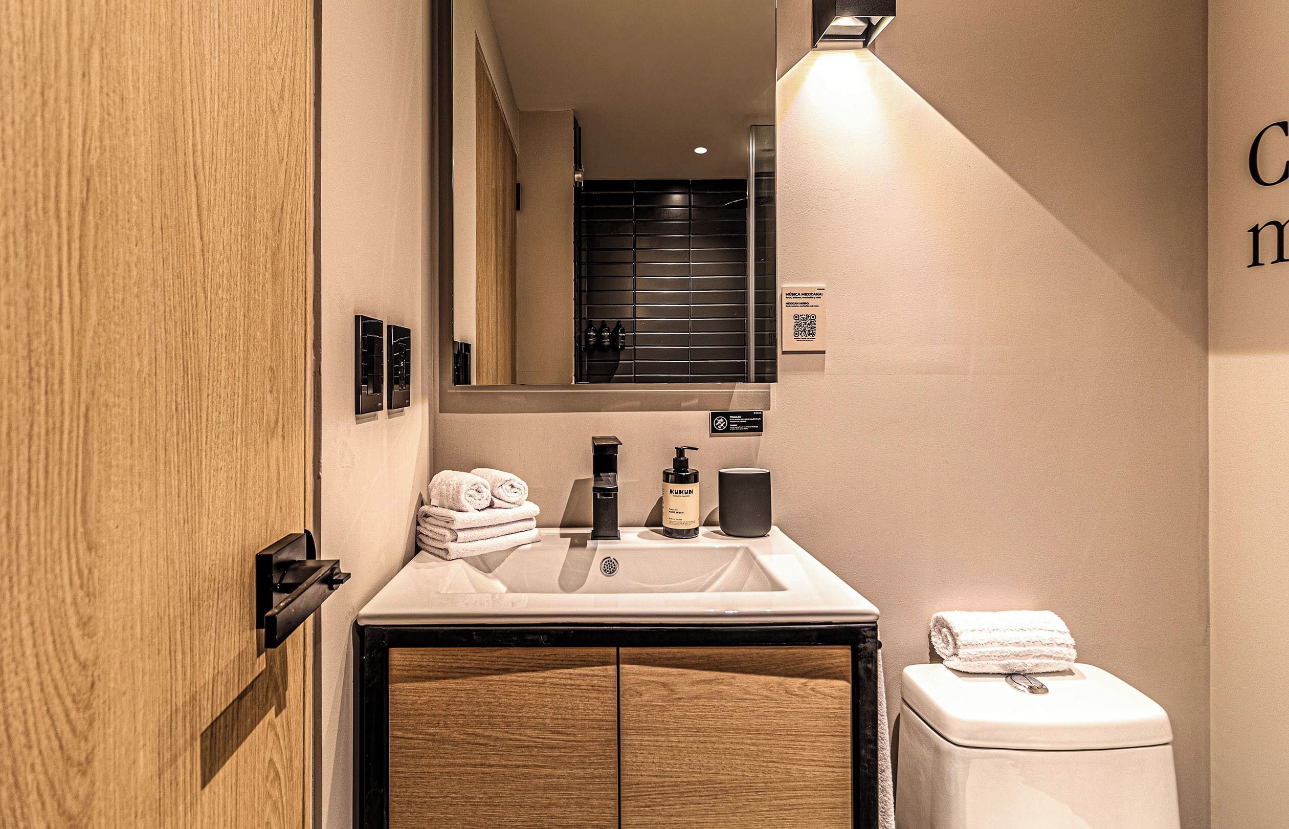 Un baño moderno con tocador de madera, lavamanos y retrete.