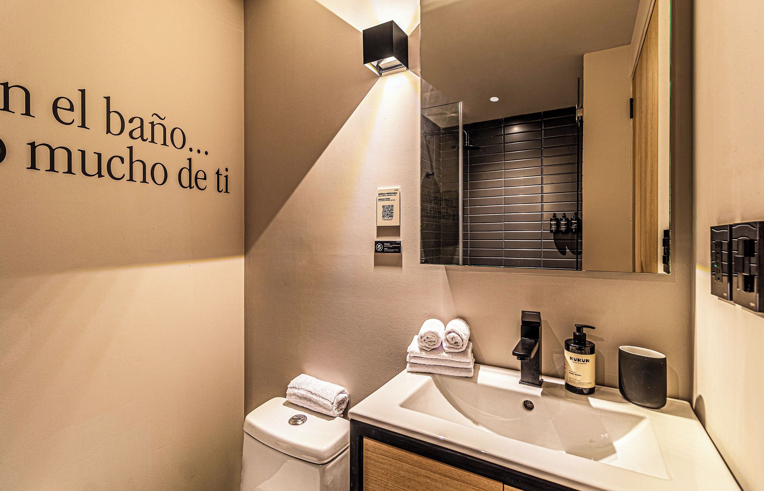 A modern bathroom with a sink, mirror, towel rack, and a wall with a motivational quote.