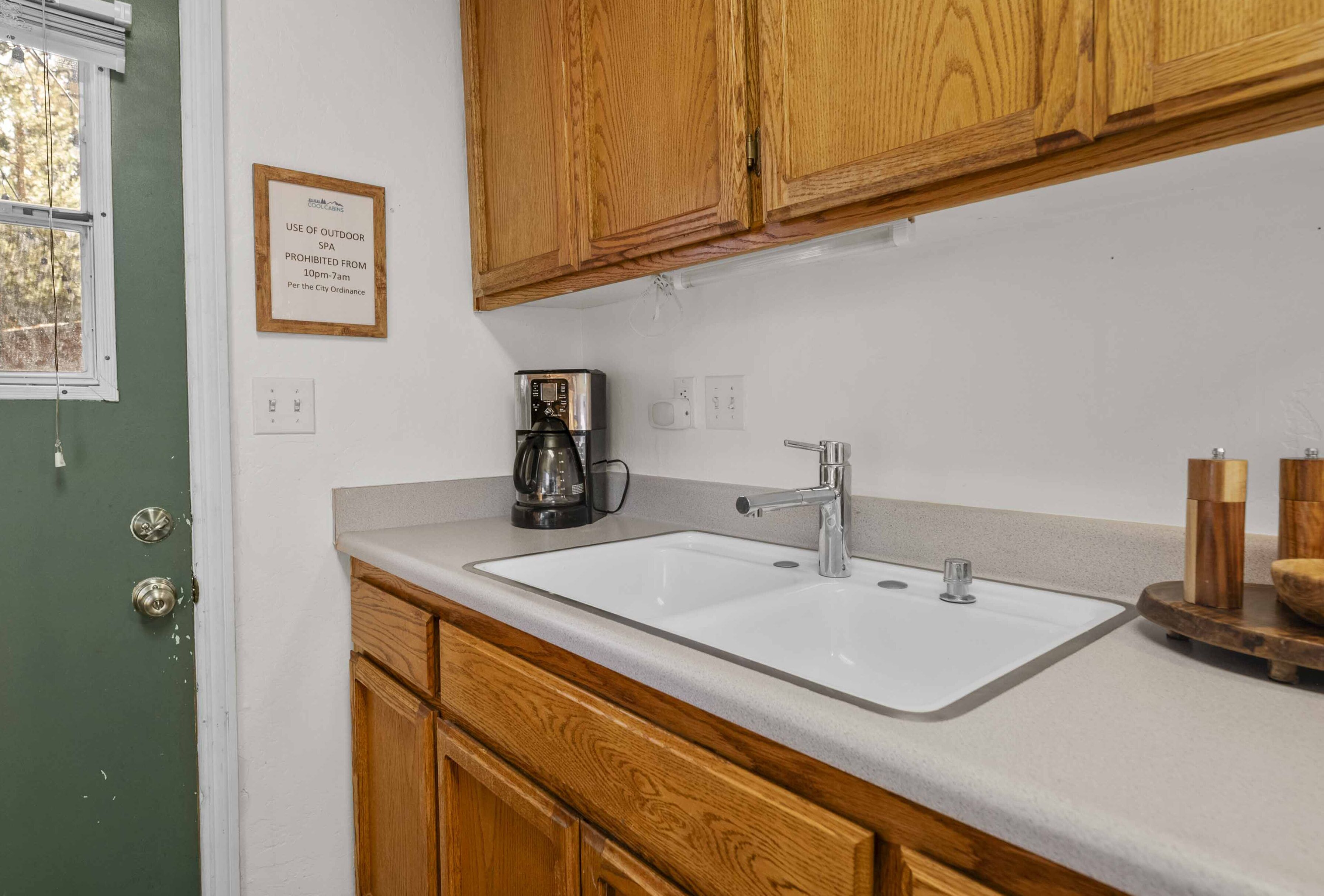 A kitchen with wooden cabinets, a white sink, and a coffee maker.