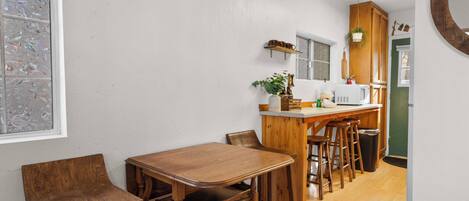 A kitchen with wooden furniture, a white wall, and a green door.