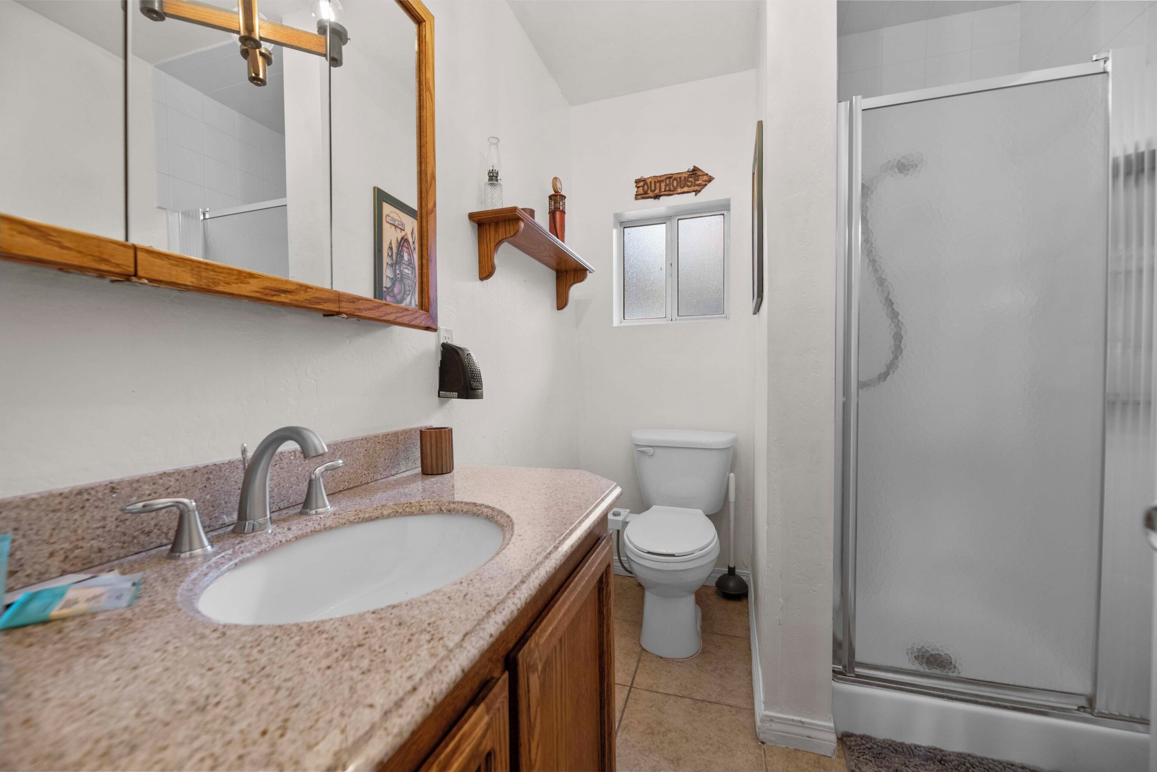 Un bagno con lavabo in granito, un water, una doccia e uno specchio con cornice in legno.