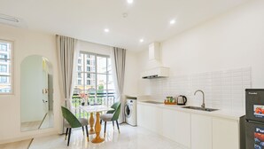 A modern kitchen with a dining area, a washing machine, and a refrigerator. - Hub Multi Hotel Phu Quoc (Phu Quoc)