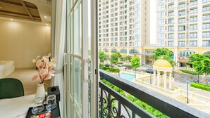 A balcony with a view of a high-rise building, a pool, and a gazebo. - Hub Multi Hotel Phu Quoc (Phu Quoc)