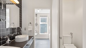 A modern bathroom with a white sink, a mirror, and a toilet. - First Tracks (Kutchan)