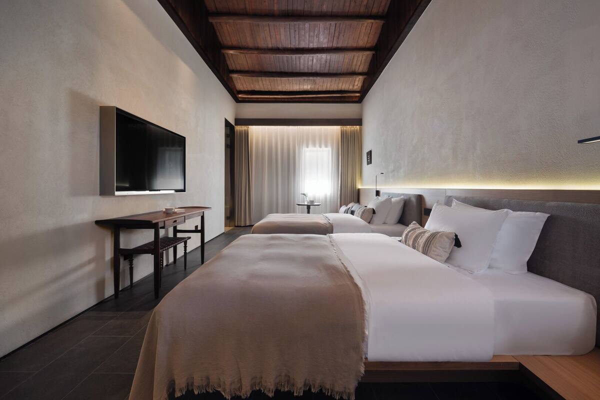 A modern hotel room with a large bed, a desk, and a TV.