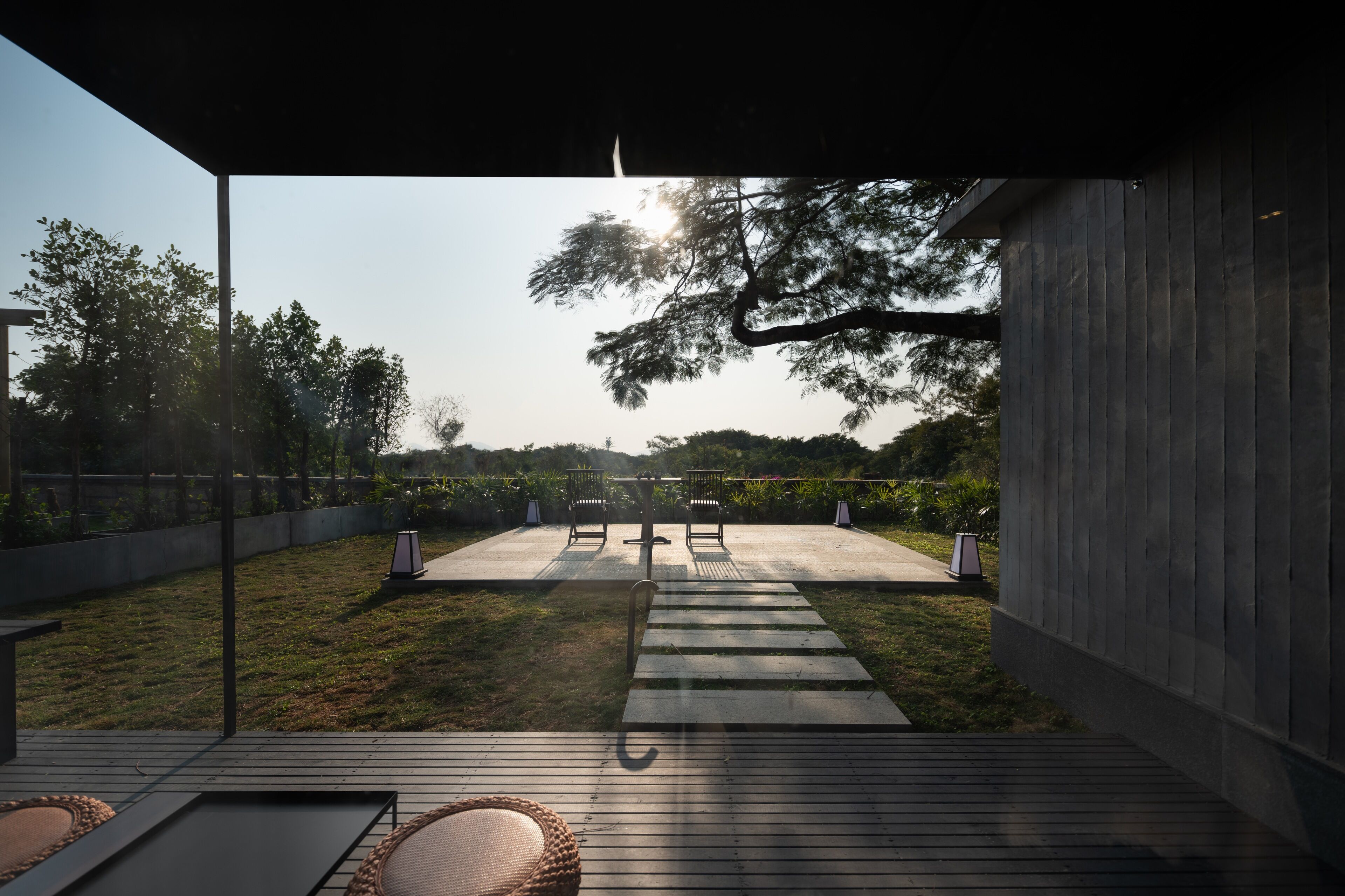 An outdoor patio with a wooden deck, two chairs, and a pathway leading to a covered area.