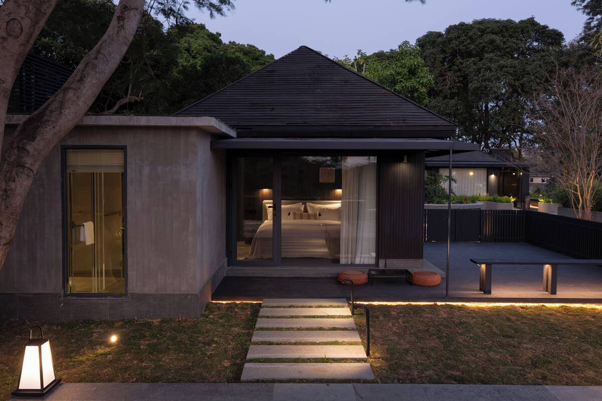 A modern house with a covered patio, a stone pathway leading to the entrance, and a bench outside.
