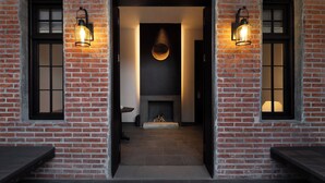Un bâtiment en briques doté d’une cheminée, de deux appliques murales allumées et d’une porte donnant sur un couloir.