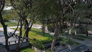 Un espace extérieur paisible, doté d’un chemin en béton, de bancs et d’une végétation luxuriante.
