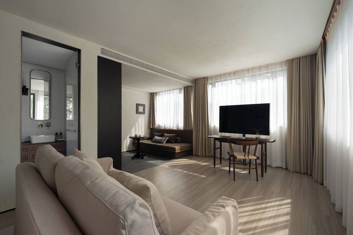 A modern living room with a sofa, a TV on a stand, and a dining table.