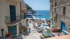 Une rue étroite bordée de bateaux amarrés le long du quai, une promenade piétonne et des immeubles dotés de balcons.