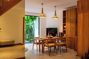 Un salon moderne avec une table à manger en bois, des chaises et un téléviseur.