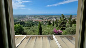 A view from a window overlooking a cityscape with greenery and distant hills. - Villa with sea view for 6 people (Pietrasanta)