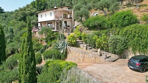 A hillside villa with a stone staircase leading to a balcony, surrounded by lush greenery and olive trees. - Villa with sea view for 6 people (Pietrasanta)