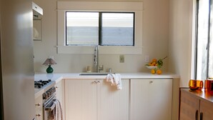 A kitchen with white cabinets, a window above the sink, and a tiled floor.