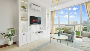 Ein modernes Wohnzimmer mit großem Fenster, einem Flachbildfernseher und einer gemütlichen Sitzecke.