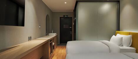 A modern hotel room with a wooden vanity, a large bed with white bedding, and a sliding door closet.
