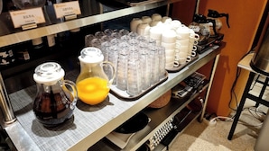 A beverage station with various drink dispensers and containers, including a pitcher of orange juice and a bottle of dark liquid. - 88Hotel (Seoul)