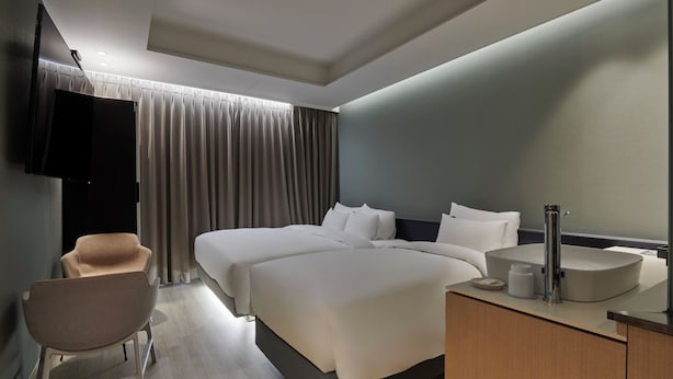A modern hotel room with a large bed, a bedside table with a sink, a chair, and a flat-screen TV mounted on the wall. - 88Hotel (Seoul)
